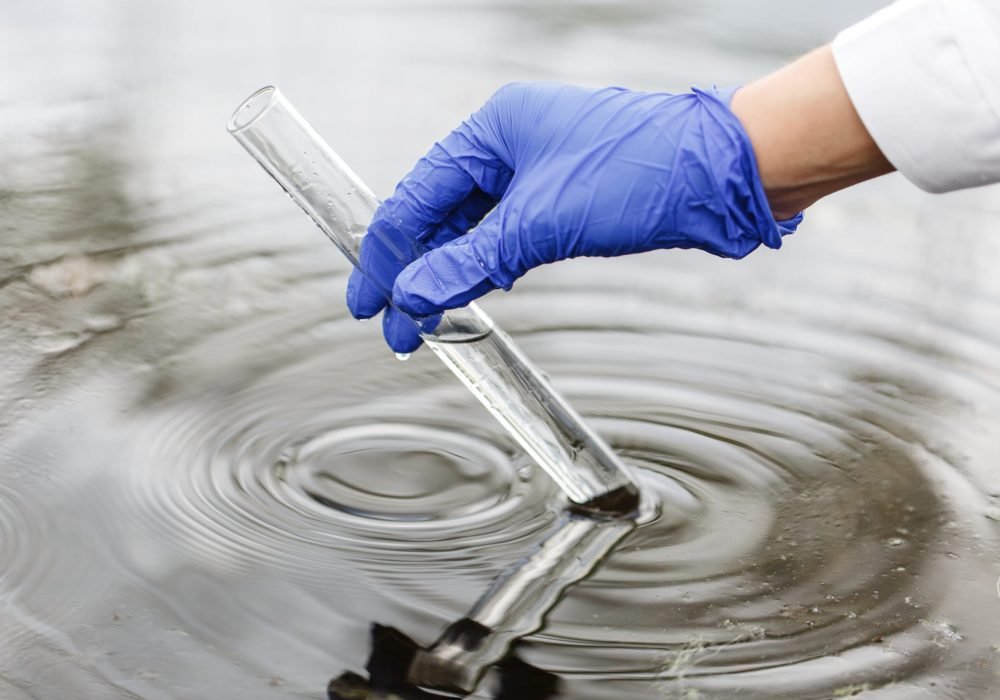 Researcher holds a test tube with water in a hand in blue glove Researcher holds a test tube with water in a hand in blue glove